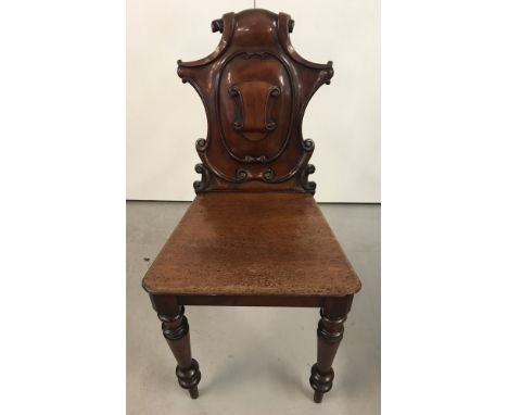 A vintage mahogany hall chair with carved scroll decoration to back and turned front legs.  