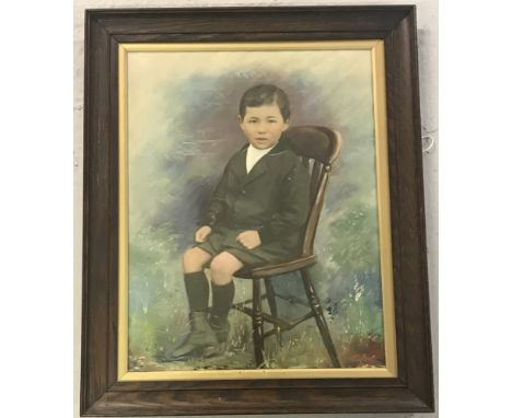 A framed and glazed oil painted photographic portrait of a young boy seated.   Picture size approx. 47 x 37cm.