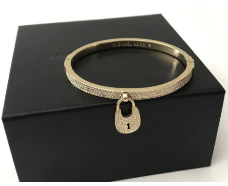 A Michael Kors gold tone hinged pave set bangle with padlock charm.  Michael Kors name to inside of bangle and back of padloc
