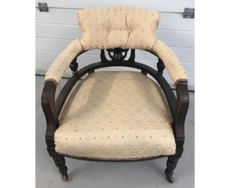 A Victorian curve backed nursing chair with turned legs and ceramic castor feet.  Carved detail to back, gold upholstery to s