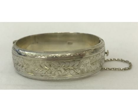 A vintage half engraved silver bangle with floral decoration, complete with safety chain.  Hallmarked Birmingham 1969. Total 