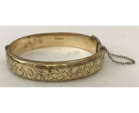A vintage 9ct rolled gold hinged bangle with half engraved decoration and safety chain.  Inside of bangle marked 1/5th 9ct Ro