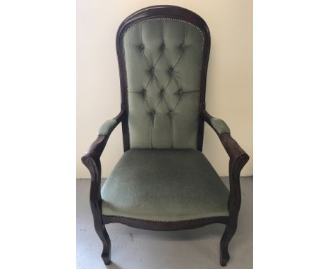 A modern dark wood framed button backed arm chair.  With green velvet upholstery, studded finish, high back and scroll detail