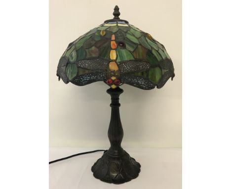 A Tiffany style table lamp with dragonfly detail to multi-coloured metal and glass shade.  Metal base has lily pad decoration