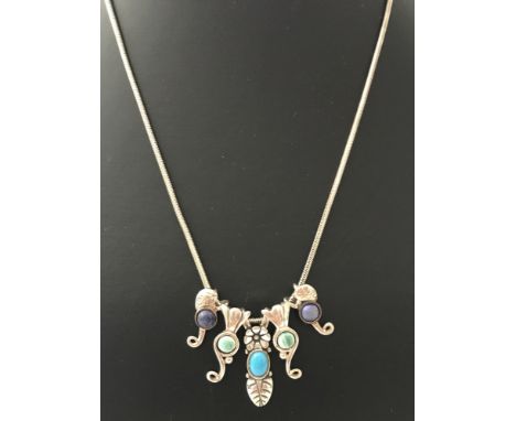 A Southwestern silver and natural stone necklace designed by Carolyn Pollock.  5 drop pendants with floral and leaf decoratio