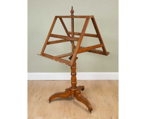 A 19th century oak double sided music or reading stand of adjustable height, with turned support on a tripod base with brass 