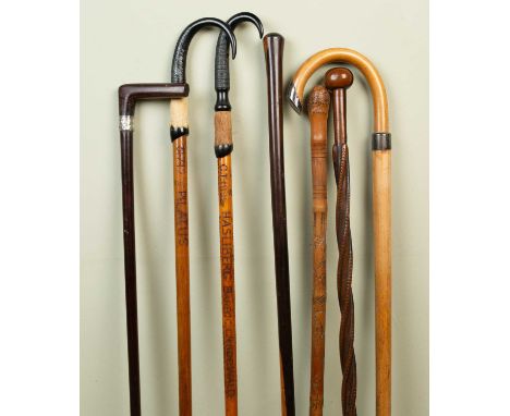 A collection of 20th century and later walking sticks and canes and a red leather cylindrical stick stand, the walking sticks