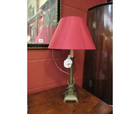 A brass table lamp on a square base, with red shade