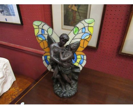 A figural table lamp of semi clad male and female with Tiffany style stained glass butterfly wings shade