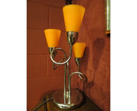 A three arm table lamp with orange glass shades