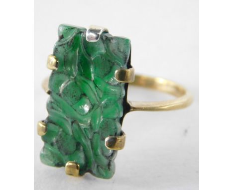 A carved jade dress ring, the rectangular carved jade panel in claw setting on a yellow metal band stamped 9K, 3.1g all in.