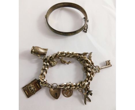 A hinged silver bangle, with vine leaf engraving, and a silver charm bracelet, with British passport, vines, swords and other