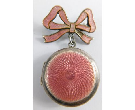 A pink enamel set locket, with pink enamelled bow top, white metal stamped silver, on brass pin back, 4.5cm high, 2cm wide, 1