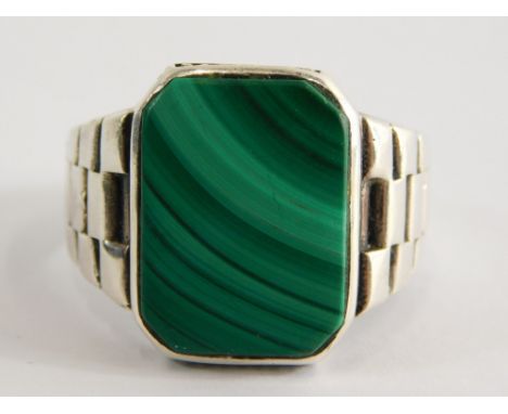 A malachite gent's signet ring, with rectangular panel in a rub over setting, with layered design shoulder, on a white metal 