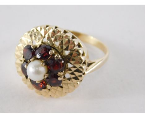 A 9ct gold garnet and seed pearl cluster ring, of chunky design, with central cultured pearl and claw setting, surrounded by 