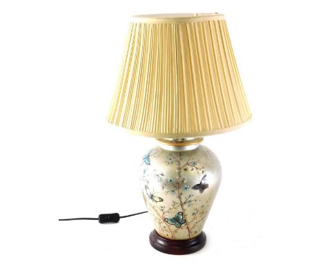 An urn table lamp, the semi porcelain urn body decorated with butterflies and flowers on a silver ground on circular foot wit