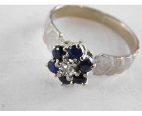 A sapphire and diamond cluster ring, set with central round brilliant cut diamond in illusion setting, surrounded by six sapp