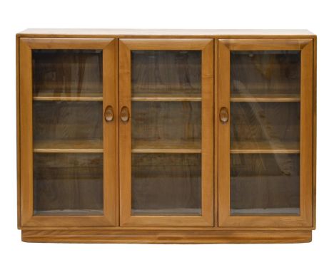 An Ercol elm bookcase, with adjustable shelves and bevelled glass lights to the doors, 97cm h; 28 x 136cm  Good condition
