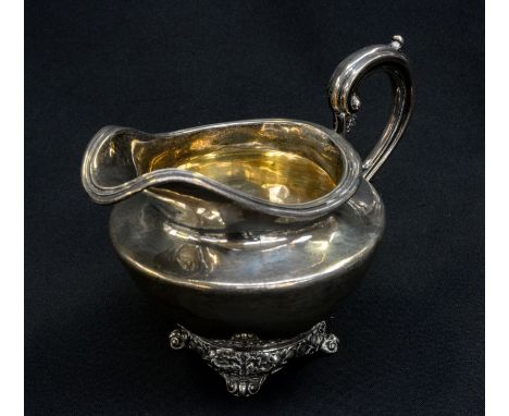 A William IV sterling silver cream jug, of ovoid form, with elaborate S scroll handle and cast foliate design with four scrol