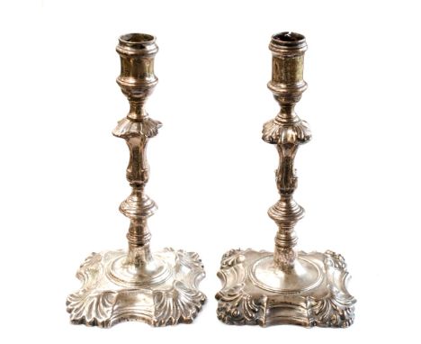 Two George II sterling silver cast candlesticks, of typical form with stepped knop baluster and foliate form on spreading squ