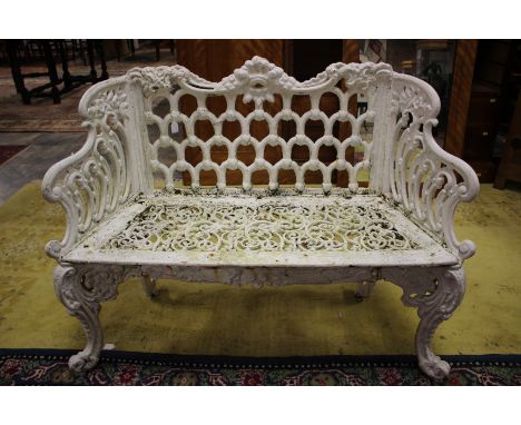 An Early Victorian white painted cast iron garden seat, in the Rococo manner, with a deep shell cast crest rail, an arcaded b