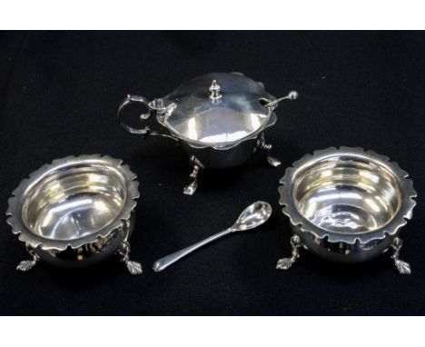 An Edwardian sterling silver matched three piece condiment set, comprising two salts, a mustard pot, a mustard ladle and a sa