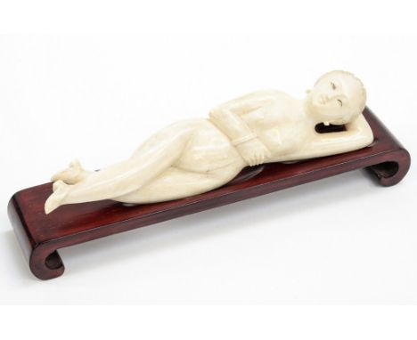 A Chinese ivory medical aid, carved as a reclining female nude, width 15cm on a wooden plinth (2) 