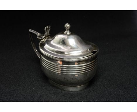 A George III sterling silver oval mustard pot, with reed banding decoration and baluster finial, shell form thumb-piece, blue