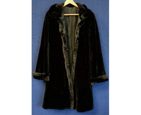 A black waterproof coat, c.1970's,  lined in a velvetine type fabric, four buttons, fur trimmed and reversable