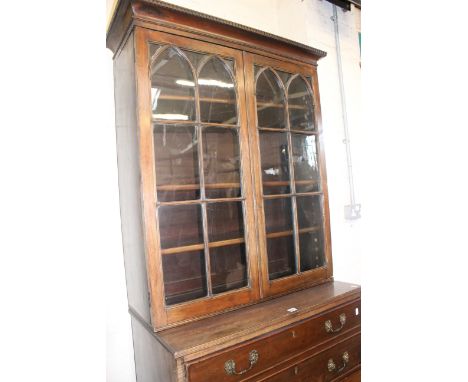 A George III and later mahogany secretaire bookcase with a dentil moulded cornice and arched astragal glazed doors enclosing 