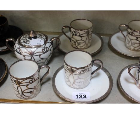 A part coffee set, white ground with silver coloured overlay, comprising of coffee pot, seven cups, six saucers, sugar bowl a