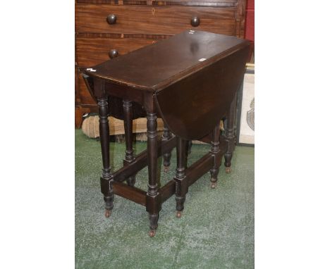 A mahogany dropleaf dining table with turned supports and ceramic casters