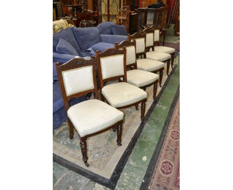 A set of six late Victorian walnut dining chairs, floral carved top rail, padded back, stuffed overseat, turned forelegs, cer
