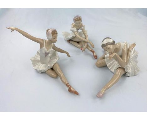 Three Nao figures of girl ballerinas doing floor exercises 