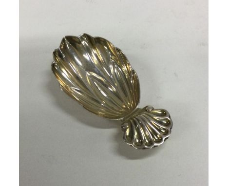 An Edwardian silver shell back caddy spoon with fluted bowl. Approx. 14 grams. Est. £20 - £30.