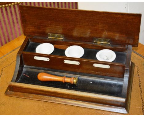 A mahogany deskstand, the hinged lid enclosing three integral ceramic inkwells, and turned wood gilt metal seal, 8cm high x 2