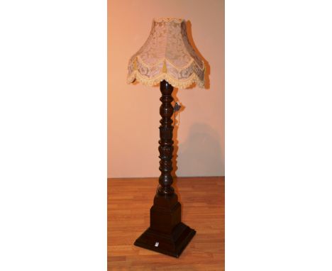 An early 20th century carved mahogany floor lamp with shade, the turned column decorated with carved stylized flowerheads, co