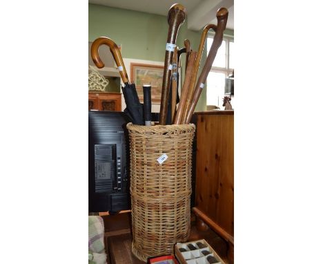 A wicker stick stand containing a selection of sticks, umbrellas, etc.