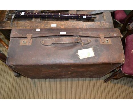 A large vintage leather suitcase with travel labels