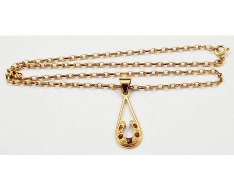 An unmarked yellow metal open drop pendant with ruby and diamond set horseshoe motif, on a hallmarked 375 chain