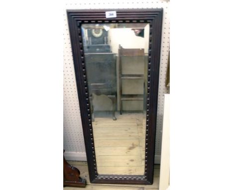 A heavy stained hardwood framed bevelled oblong wall mirror with moulded decoration