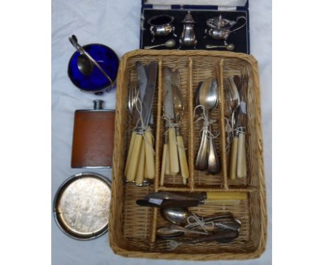 A wicker cutlery tray containing a cased silver plated three piece condiment set, plated cutlery, leather clad hip flask, etc