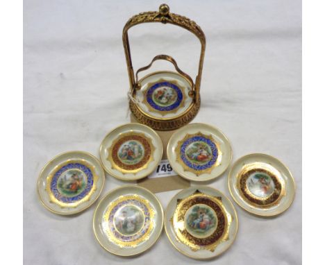 A gilt metal stand containing six ceramic coasters in the Vienna style