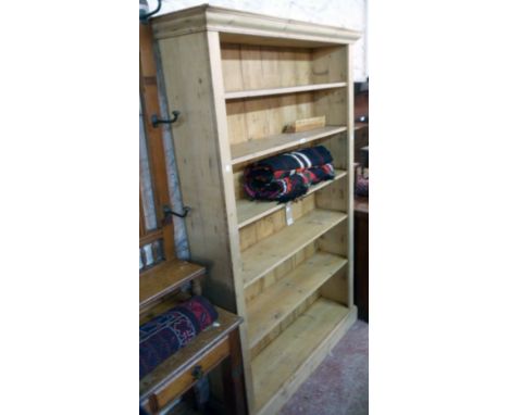 A 4' 3" stripped pine six shelf open bookcase with moulded cornice and plinth base - 6' 9" high