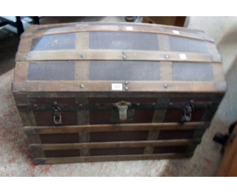 A late Victorian wood and metal bound dome top travelling trunk with canvas weather coating, flanking leather carrying handle