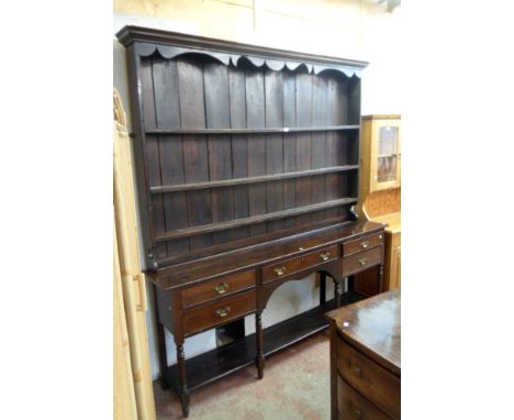 A 7' late Georgian stained oak two part dresser with moulded cornice and shaped frieze to the three shelf open plate rack, ov