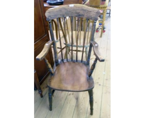 An antique stained mixed wood stick back elbow chair with solid moulded seat, set on ring turned supports