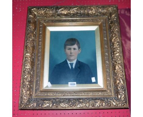 An ornate gilt gesso box framed and slipped overpainted photographic portrait of a boy