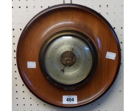 A retro moulded polished wood cased circular wall barometer with visible aneroid works to dial centre