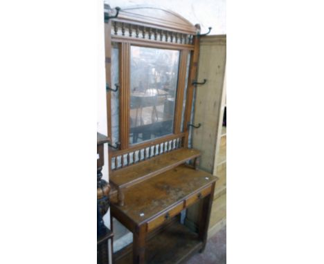 A 36" late Victorian stained oak hallstand with a spindle set top, central mirror, flanking hooks and shelf over two frieze d